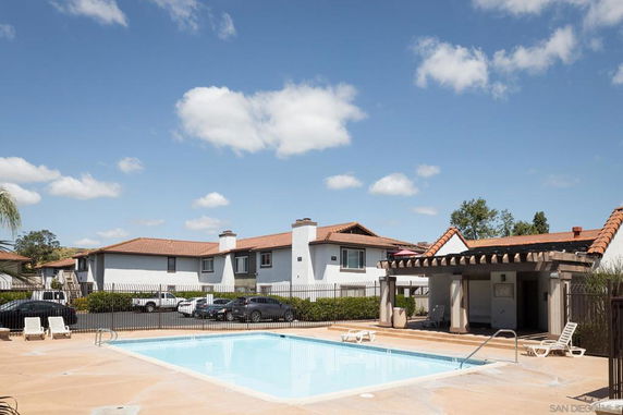 Outdoor swimming pool area with surrounding residential buildings and lounge chairs.