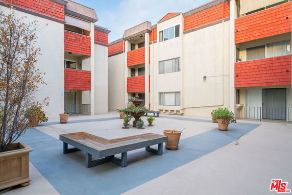 Courtyard area of a residential building complex with benches and potted plants.