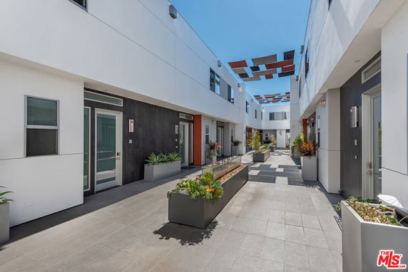 View of a modern apartment building with a courtyard and potted plants.