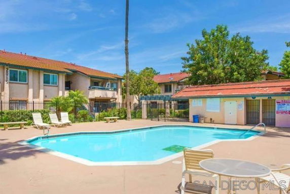 Outdoor swimming pool area with lounge chairs and nearby building.