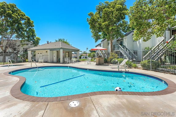 Outdoor swimming pool area with adjacent buildings and a small pavilion.