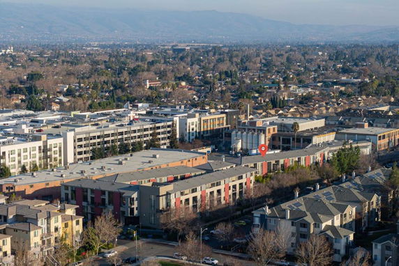 Panoramic view of urban area with multiple buildings and distant hills.