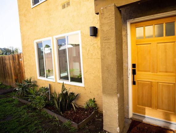 Front view of a house with a brown stucco exterior and a wooden entry door.