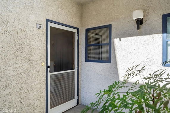 Front entry view of a house with a screened door and window with blue trim.