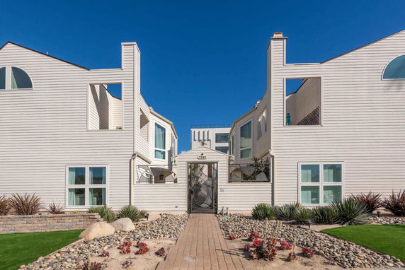 Front view of a modern two-story building with light siding and large windows.