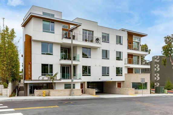 Front view of a modern multi-story building with balconies and large windows.