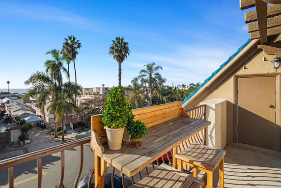 Rooftop view with patio seating and surrounding palm trees.
