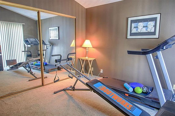 Home gym area with exercise equipment and mirrored closet doors.