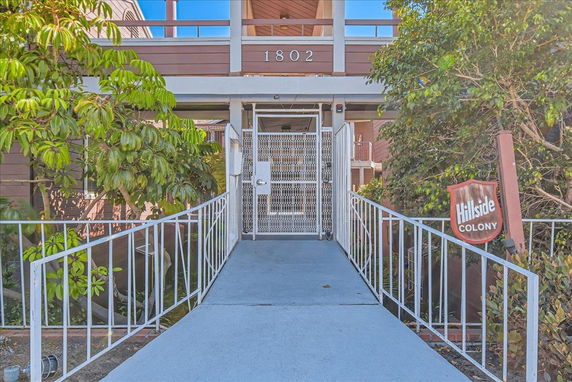 Front view of a building entrance with a walkway leading to a gated entry.