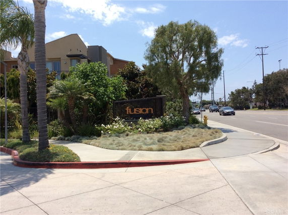 Front view of a residential complex sign with buildings in the background.