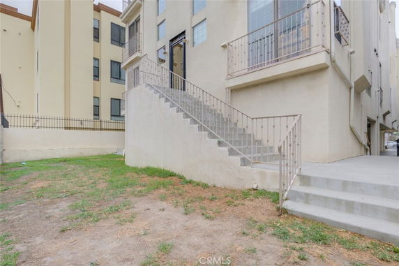 Side view of a multi-story building with an exterior staircase and balcony.