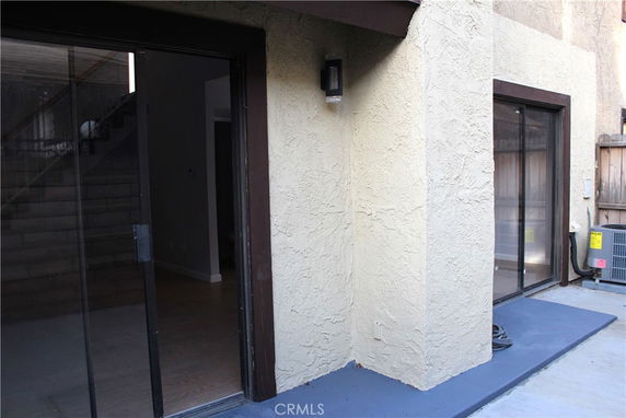 Corner view of a building with sliding glass doors and an air conditioning unit outside.