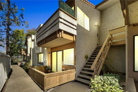 Front view of a multi-story building with wooden balconies and an exterior staircase.