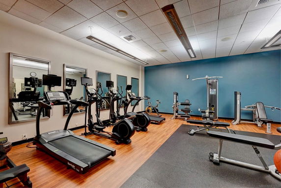 Indoor gym area with various exercise equipment and mirrors.