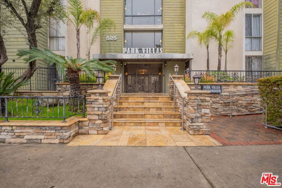 Front view of a condominium entrance with stone steps and railing.