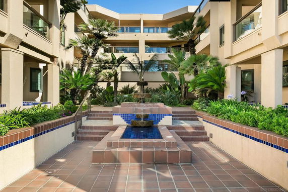 Front view of a multi-story building with landscaped courtyard.