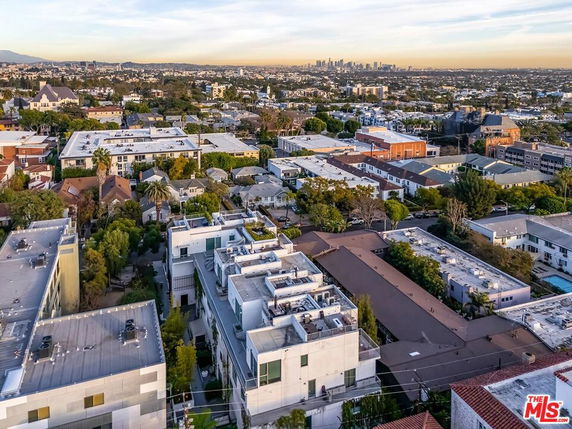 Panoramic view of a residential area with multiple buildings and a distant city skyline.