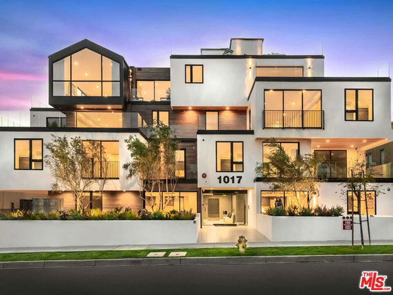 Front view of a modern multi-story building with large windows and unique architectural design.