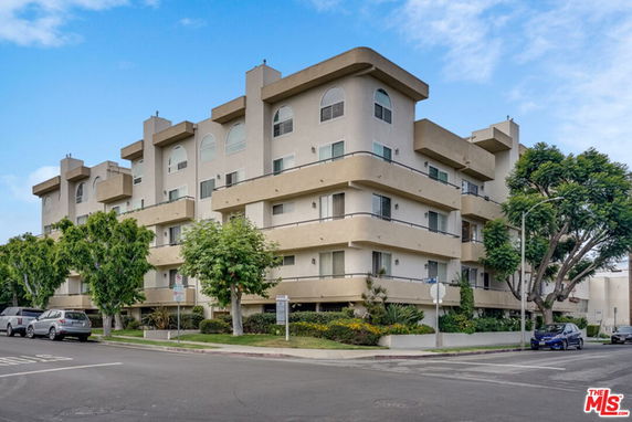 Front view of a multi-story apartment building on a street corner.