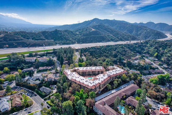 Aerial view of a residential complex surrounded by hills and roads.