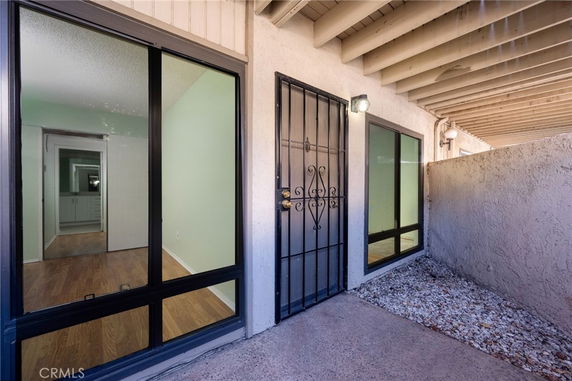 Front view of a small building entrance with metal grille door and large windows.