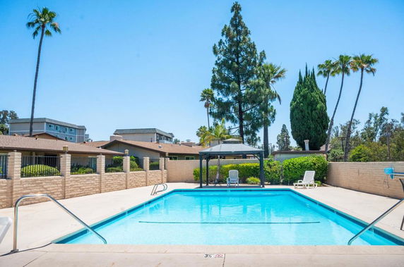 Outdoor swimming pool with surrounding fence and trees.