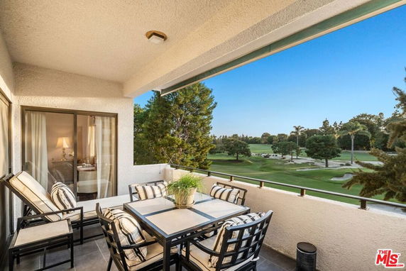 Balcony with outdoor seating overlooking a golf course and treed landscape.