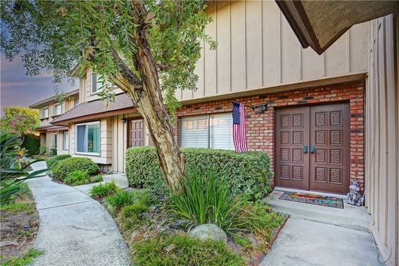 Front view of a two-story house with an American flag and a double door entry.