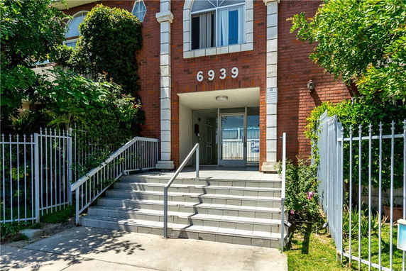 Front view of a brick building entrance with steps and a metal railing.