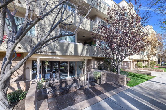 Front view of a multi-story residential building with balconies and entrance steps.