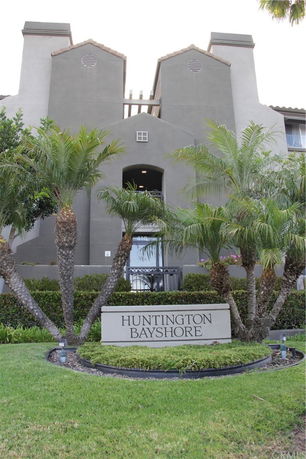 Front view of a building with palm trees and a sign reading 'Huntington Bayshore'.