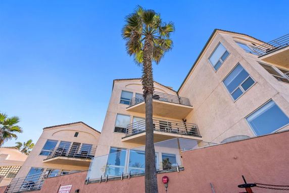 Front view of a multi-story building with balconies and a pink exterior wall.