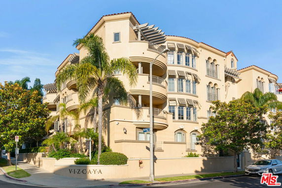 Front view of a multi-story building with balconies and palm trees