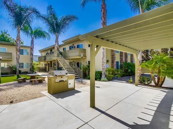 Outdoor area with multi-story building, patio, and barbecue setup.