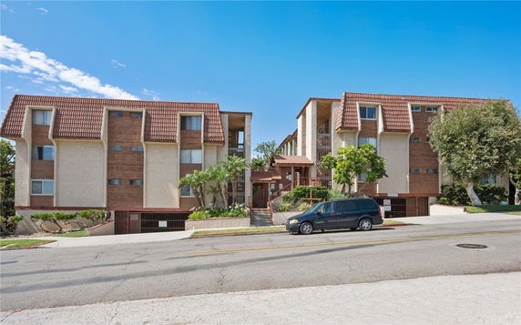 Front view of an apartment complex with a distinct roof design and multiple levels.