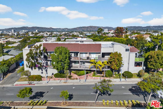 Front view of a multi-story building with balconies and flat roof.