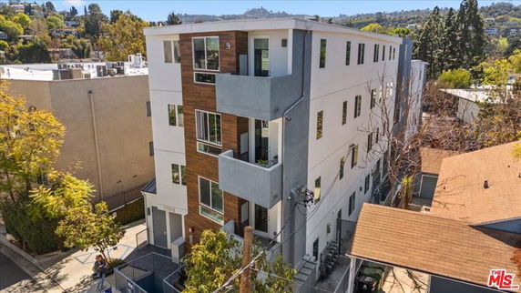 Front view of a multi-story modern apartment building with a mix of white and wood paneling.