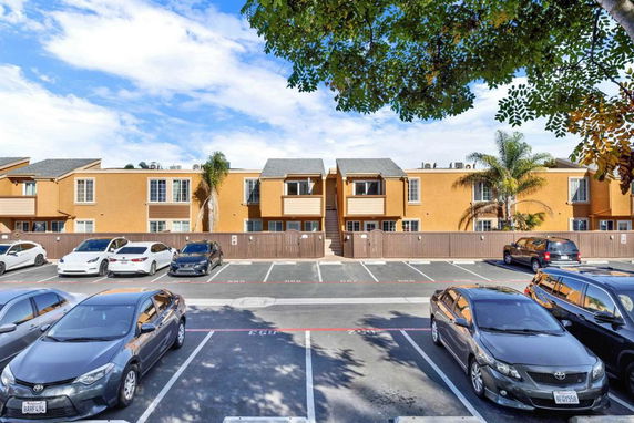 Outdoor parking area in front of a tan apartment building.