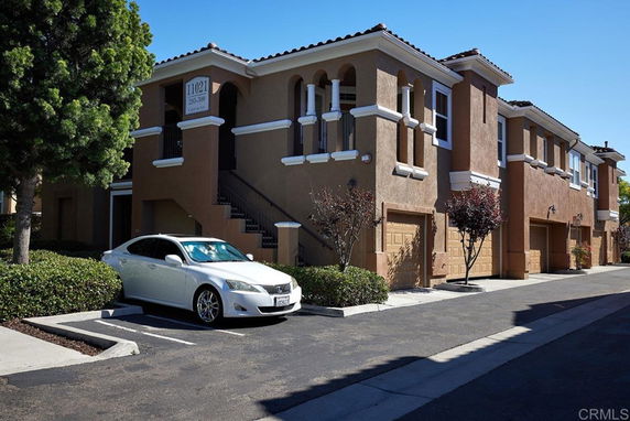 Front view of a two-story building with garages and arched balconies.