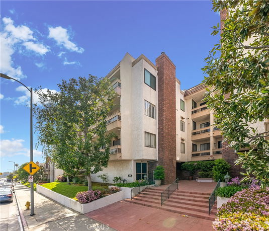 Front view of a multi-story residential building with balconies and a brick facade.
