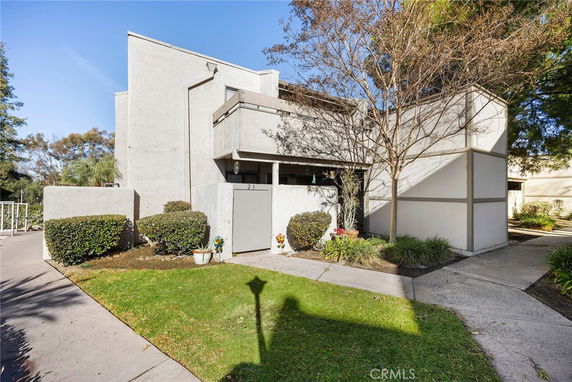 Front view of a modern two-story building with geometric design and a small garden area.