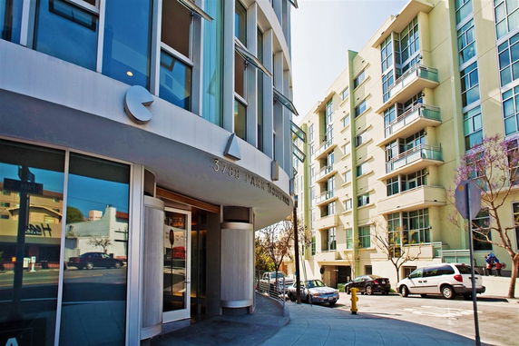 Front view of a modern multi-story building with glass windows and balconies.