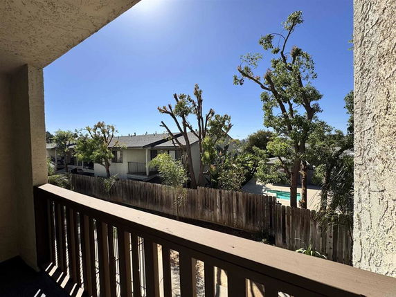 View from balcony overlooking neighboring houses and trees.