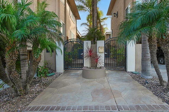 Front view of a building entrance with decorative metal gates and surrounding palm trees.