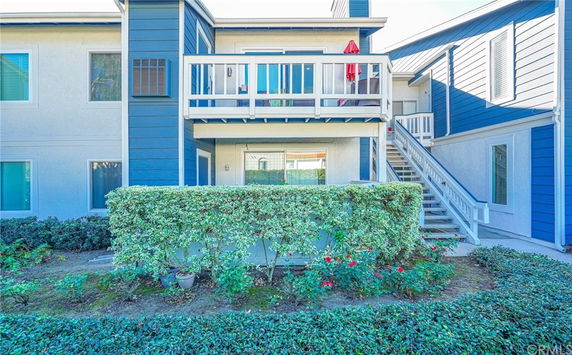 Front view of a two-story building with a balcony and staircase.