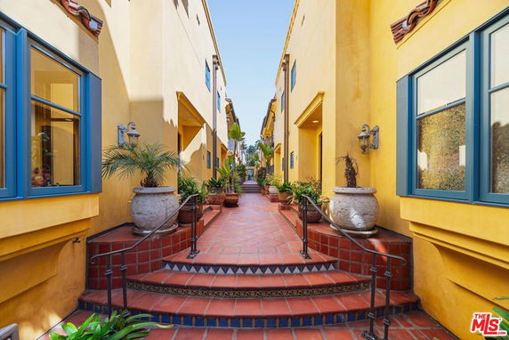 View of a walkway between two parallel buildings with yellow walls and blue window frames.