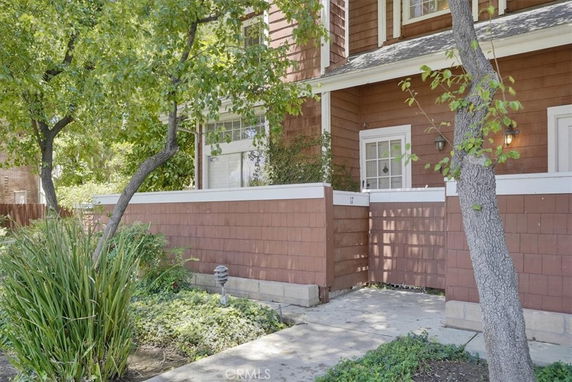 Front view of a brown two-story house with white trim and an external enclosed patio.