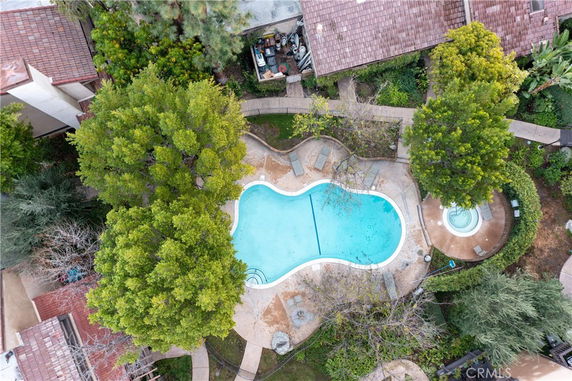 Aerial view of a swimming pool surrounded by trees and a residential area.