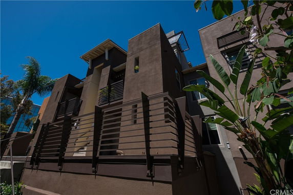 Front view of a modern multi-story building with brown facade and metal railings.
