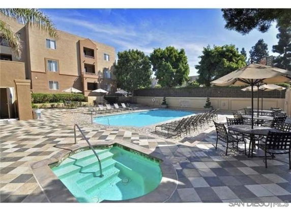Outdoor swimming pool area with adjacent hot tub and seating.